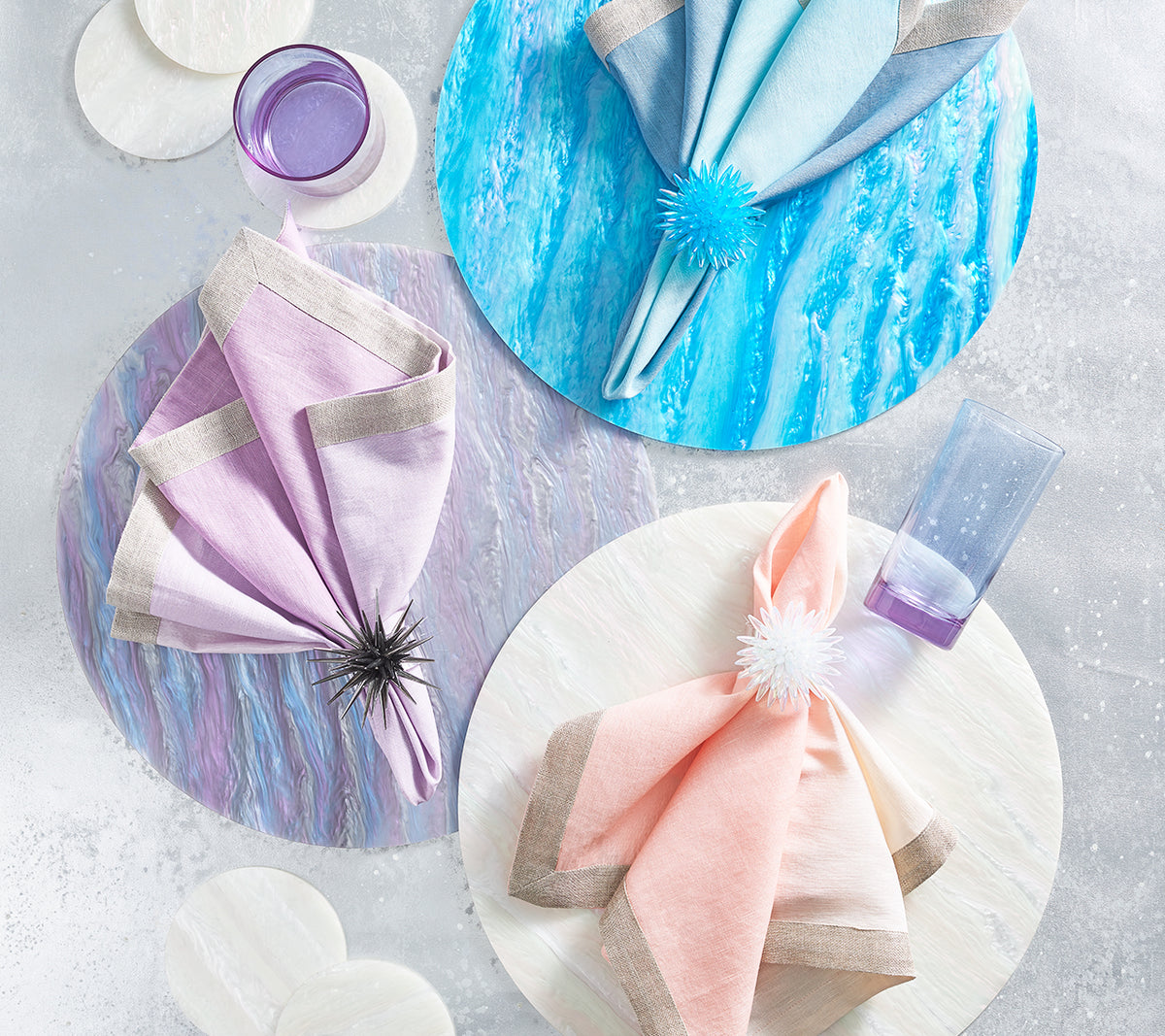Blush linen napkin with a metallic border arranged on a pastel table setting with glassware