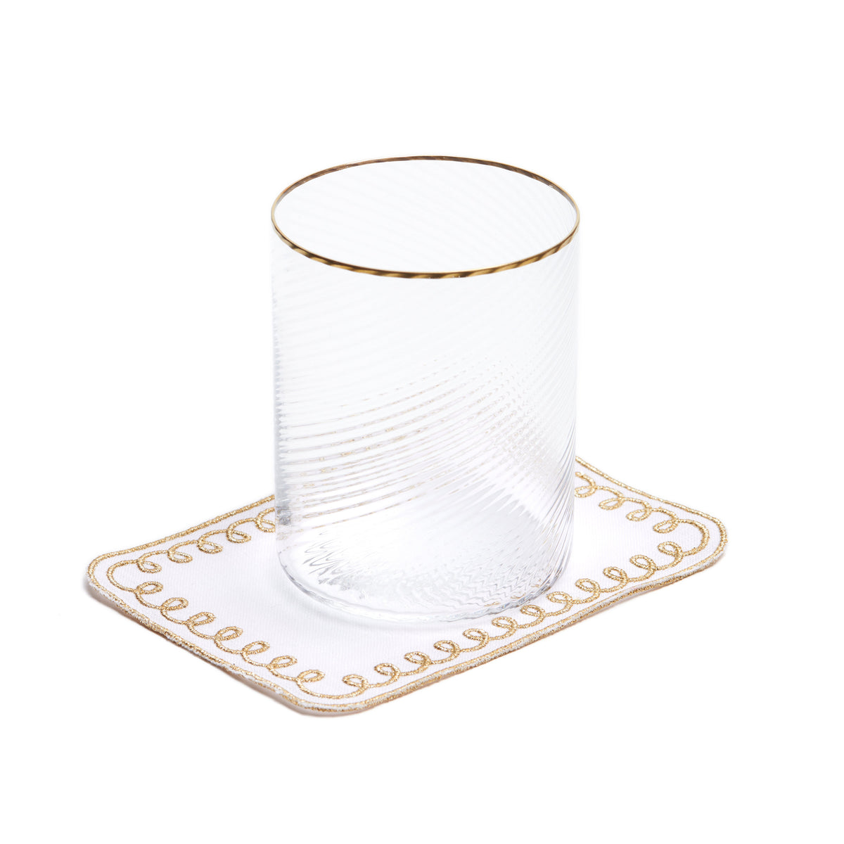 Top view of Golden Loopy cocktail napkin on white Belgian linen with hand stitched gold loopy border and clear glass