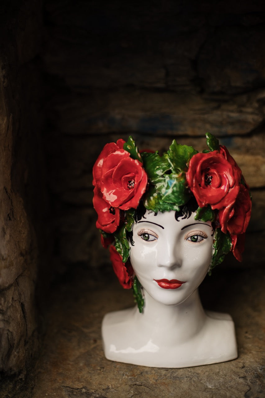 Three-quarter view of Sicilian Heads Poppies head showcasing hand-painted red poppy crown and glossy glaze against a rustic stone background