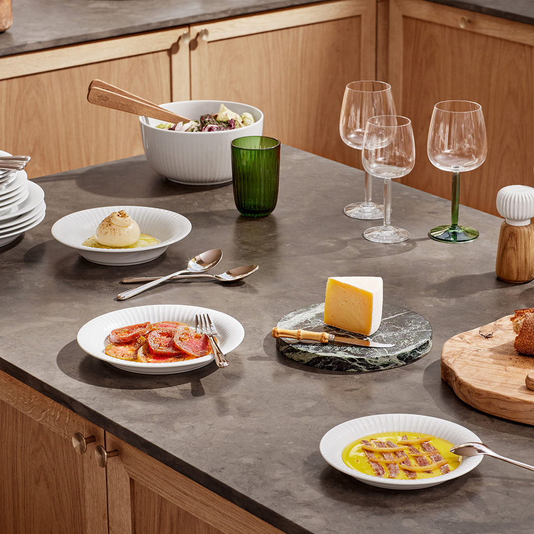 Oak salad server set resting in a salad bowl on a styled kitchen dining table