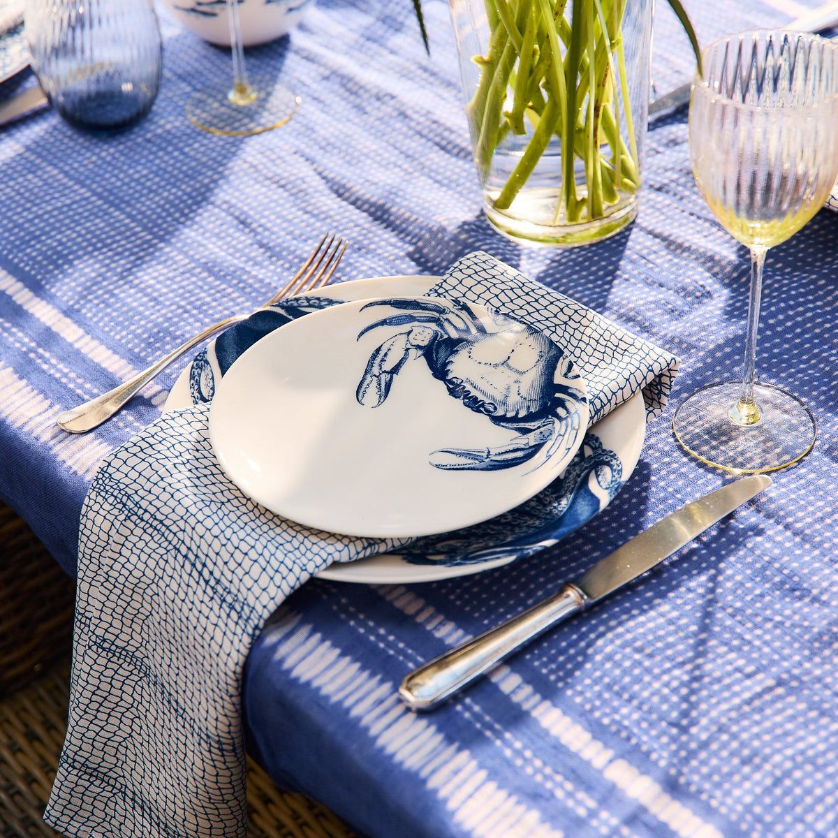 Angled view of Catch Dinner Napkins, Set of 4 showcasing an organic geometric pattern on a coastal table