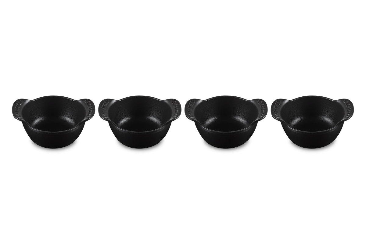 Angled view of four Mini Round Cocotte Base 1/3 QT pieces in matte black showcasing curved handles on a white background