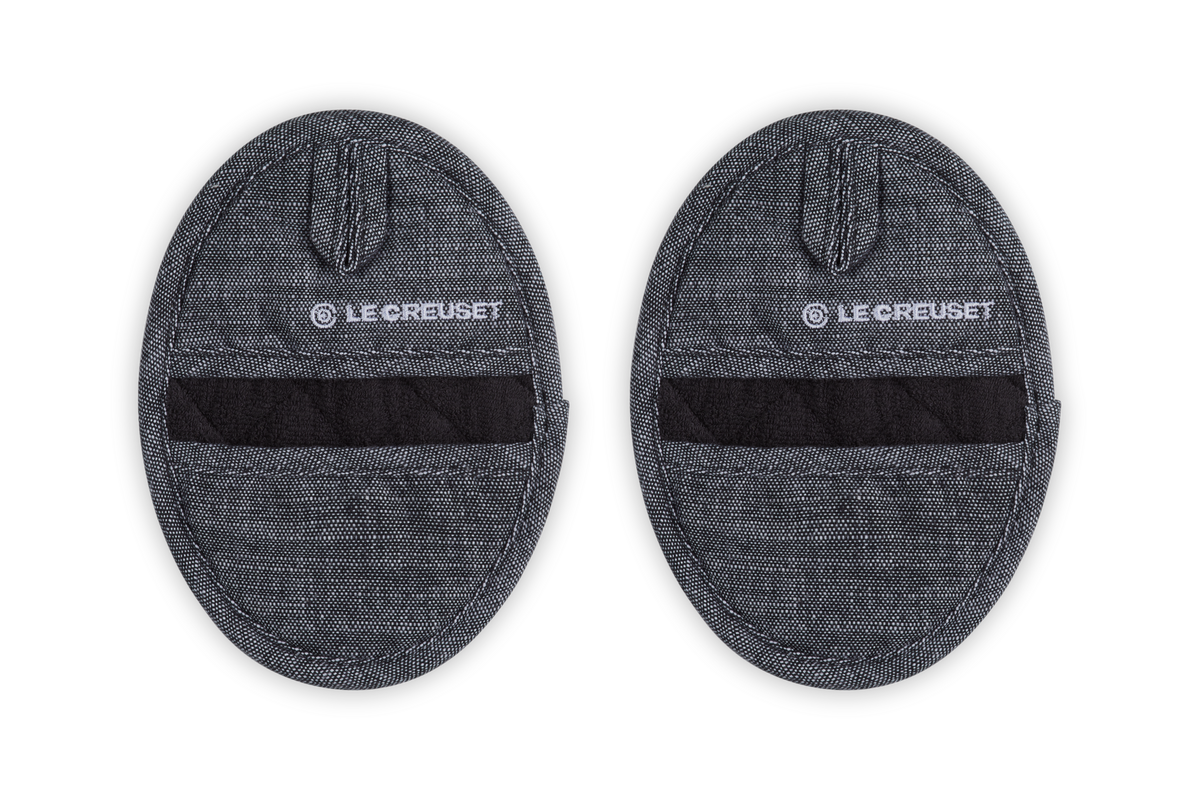 Close-up of Pot Grips Noir, Set of 2 showcasing textured black silicone grips with terry cloth lining on a black background