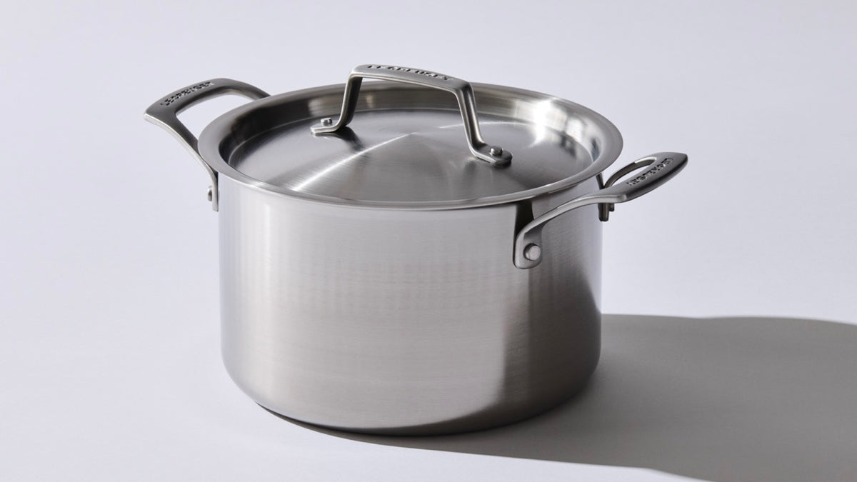 Angled view of Classic Stockpot 10 qt showcasing satin-matte stainless steel finish, lid, and loop handles on a light gray background