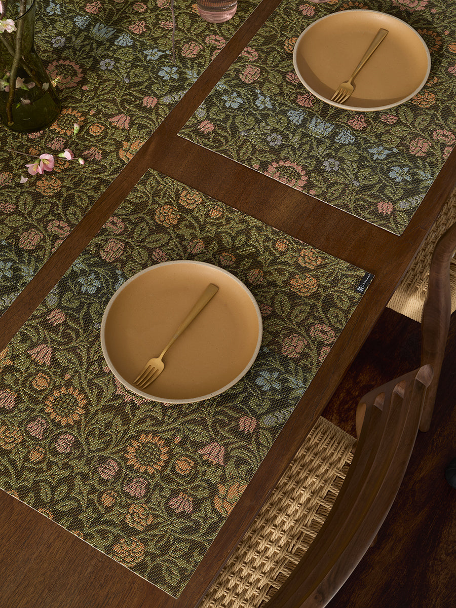Top-down view of William Morris placemat in Dark Multi showcasing intricate floral woven pattern on a dark wood dining table