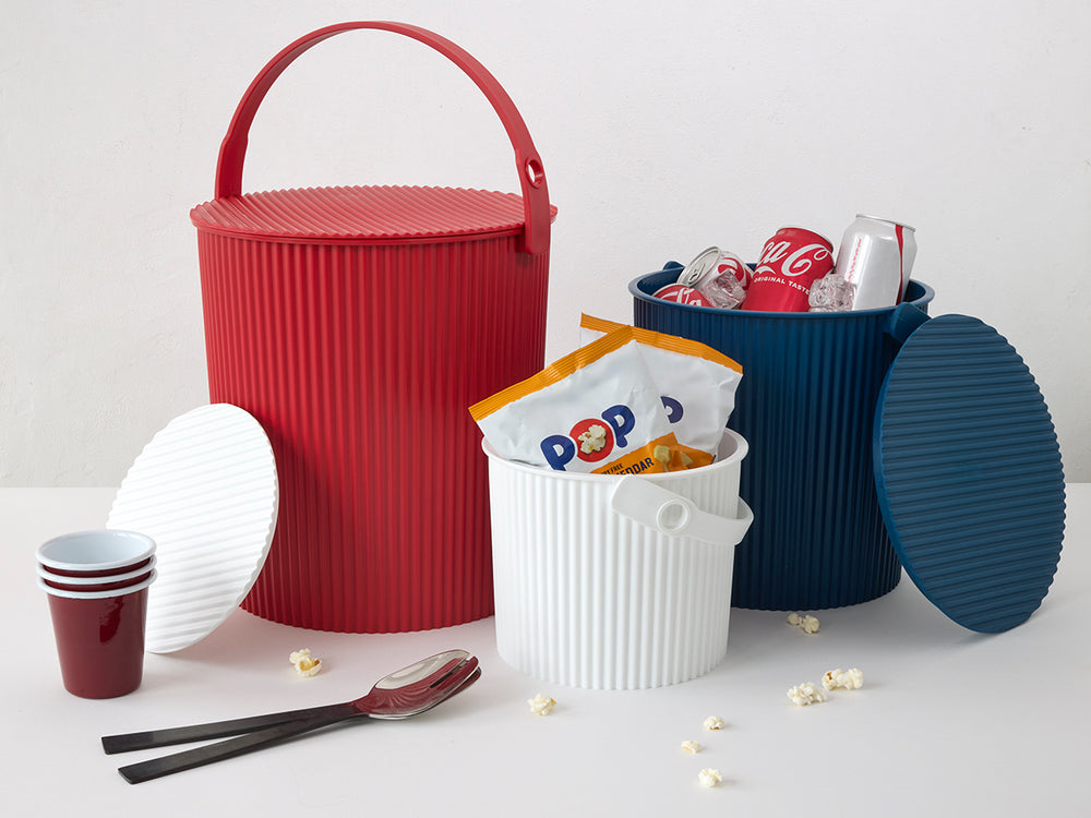 Front view of Hachiman extra-large red bucket showing lid and handle on a white tabletop with blue and white buckets nearby
