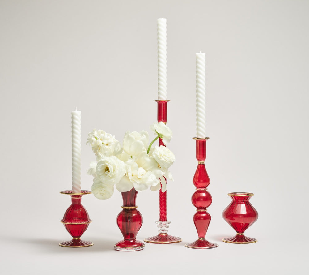 Front view of Trumpet Bud Vase in Ruby with 18K gold bands, shown with red glass candlesticks and white taper candles