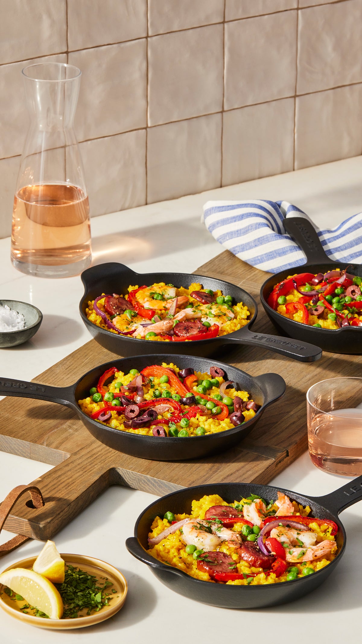 Top view of matte black mini skillet 1/3 qt showing cast-iron texture, set of four on wooden board with paella