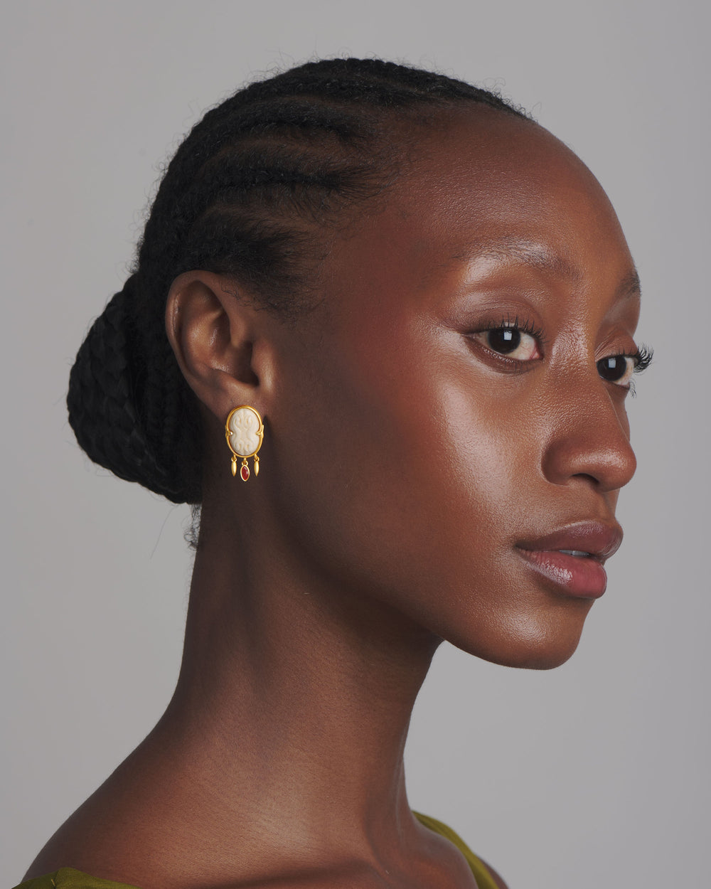Side profile of The Cinched Cameo Earrings showing hand-carved bone cameo in gold setting with carnelian drops on gray background