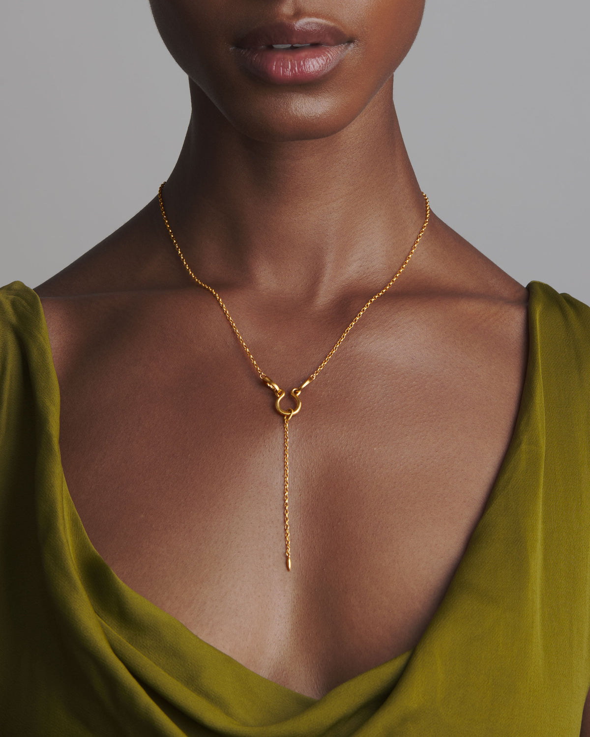 Close-up of Keeper of All Treasures lariat necklace on model showing gold-plated lariat drop and delicate chain on olive green draped top