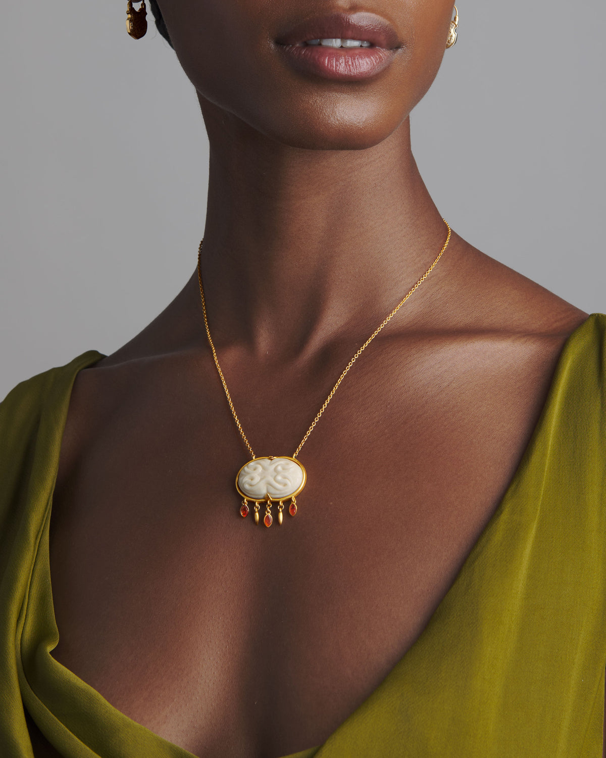 Close-up of Cinched Cameo Necklace on model showing hand-carved bone cameo with gold bezel and carnelian drops on a chain