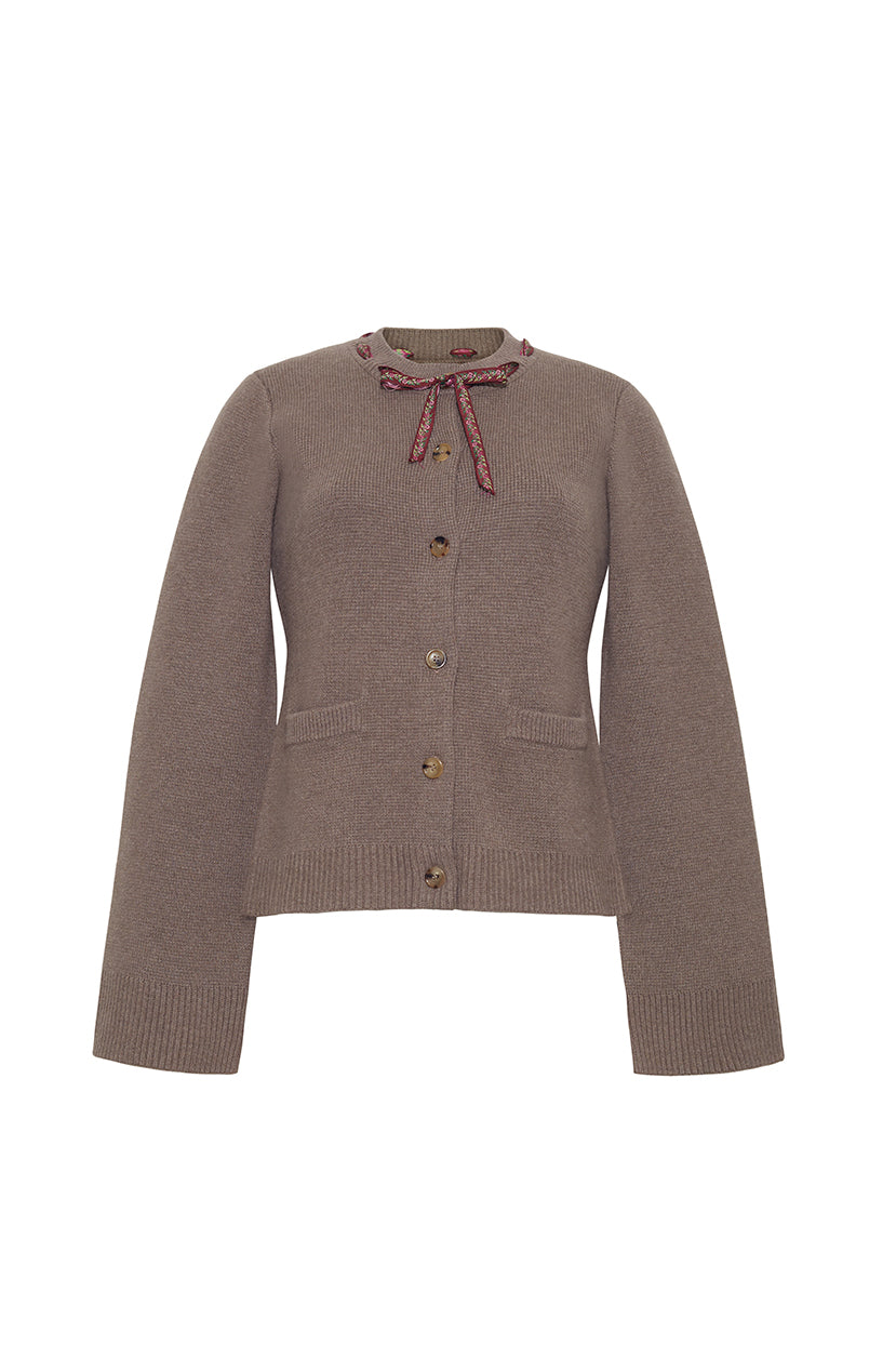 Front view of Alma Cardigan showcasing taupe knit, button front, ribbon bow tie at neckline, patch pockets and ribbed cuffs on white background