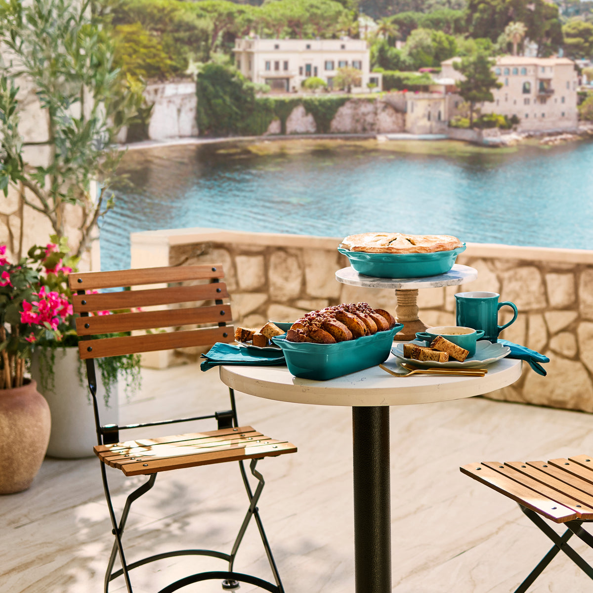 Vancouver mug in Riviera on a small table with matching turquoise bakeware and pastries on a sunlit seaside terrace