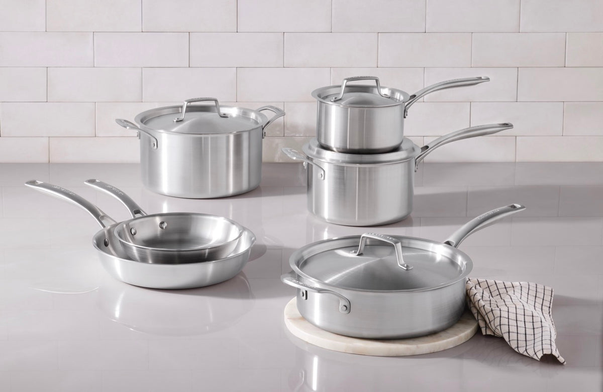 Front view of Essential Stainless Steel 4 qt saucepan with lid, brushed finish and interior capacity markings on a tiled kitchen countertop