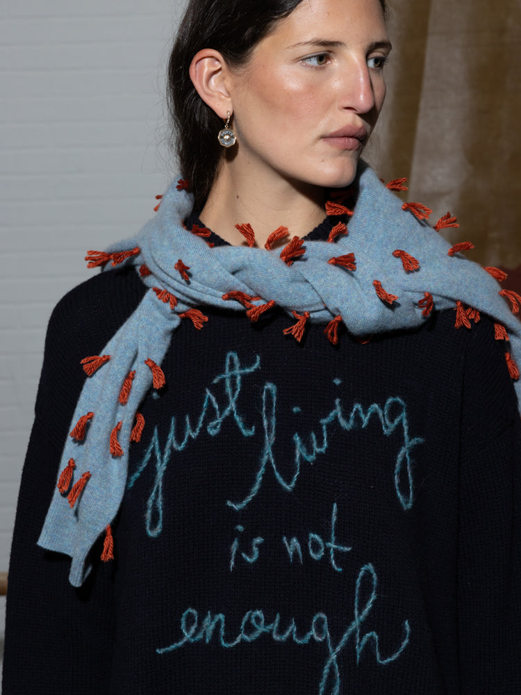 Front view of Just Living Is Not Enough crewneck in navy showing embroidered script reading just living is not enough, worn oversized on model