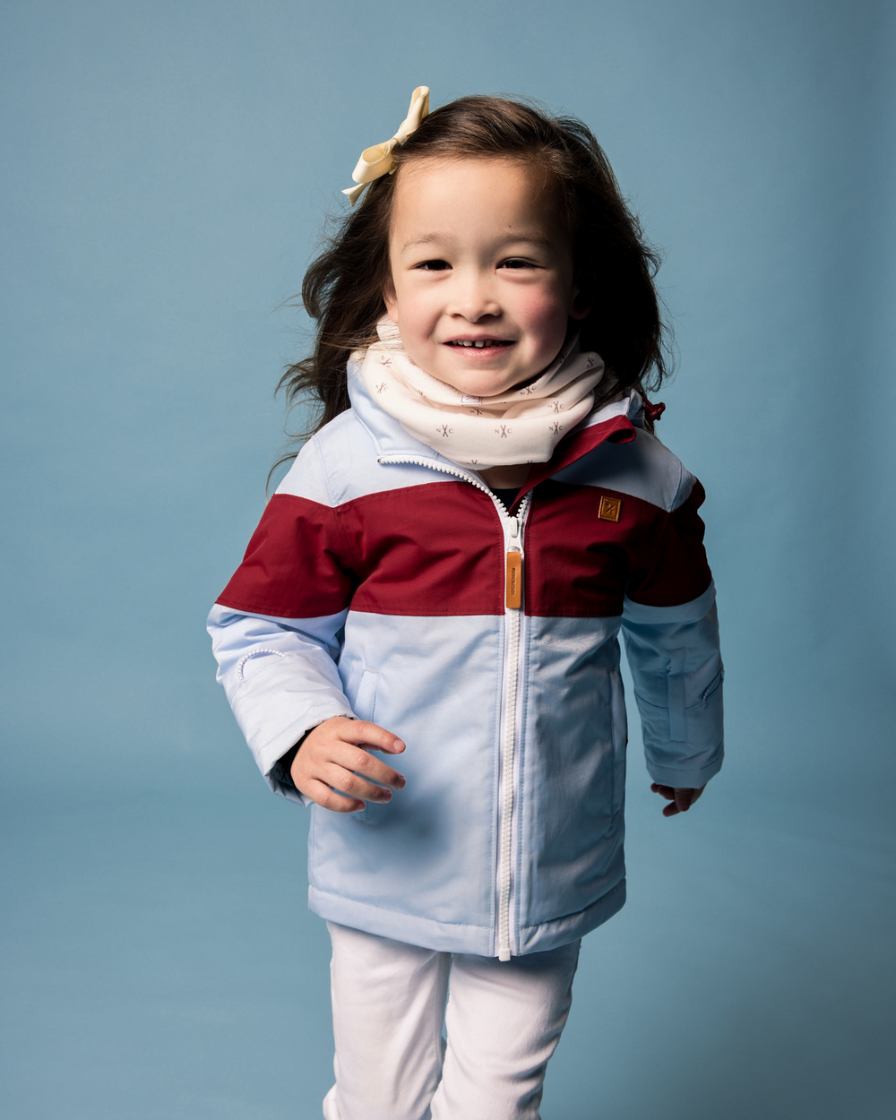 Front view of NC Skis fleece-lined neck warmer on a child model showcasing soft microfleece lining and snug fit on a light blue background