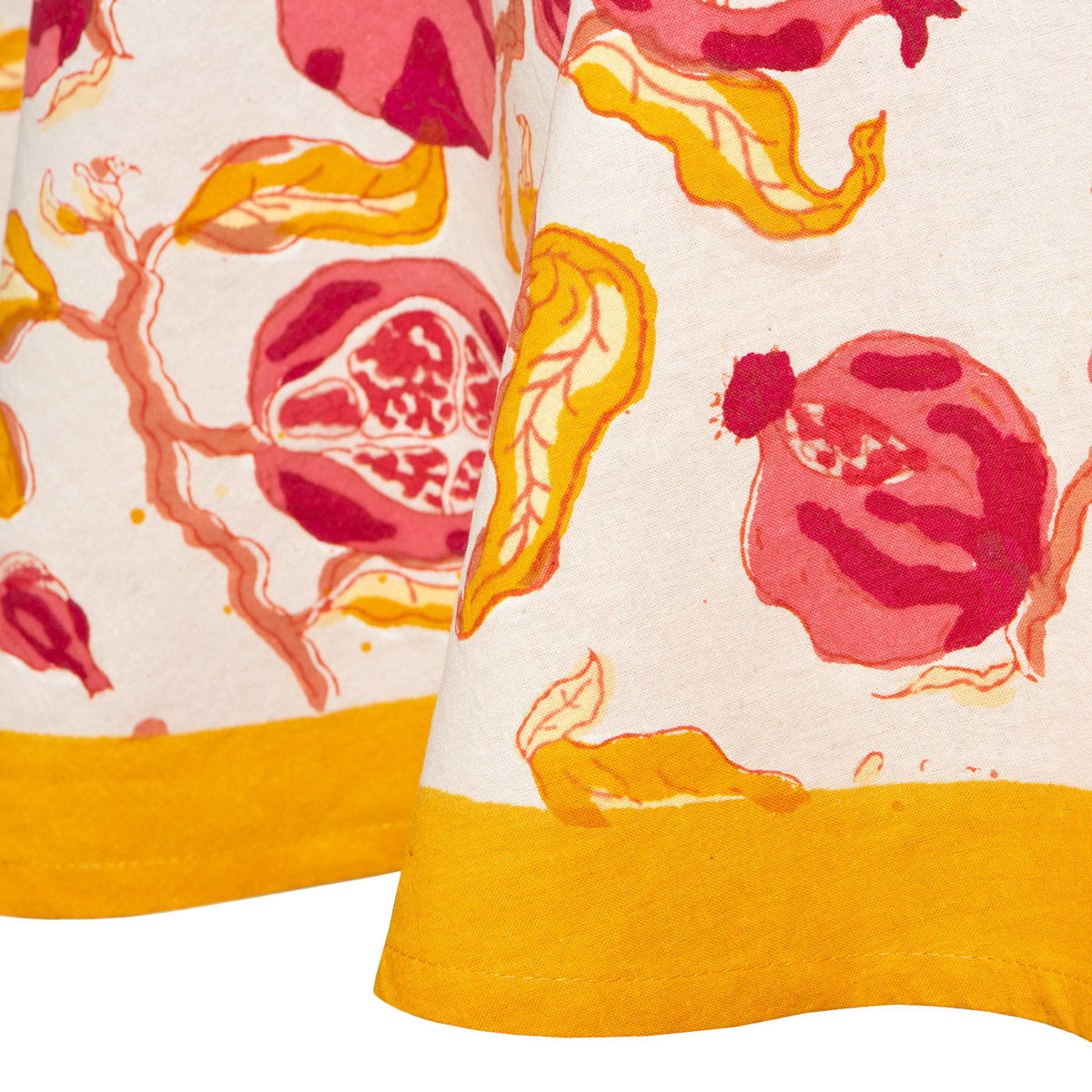 Close-up of French Tablecloth Pomegranate showcasing hand-painted pomegranate pattern in ruby red and citrine yellow on a cream background