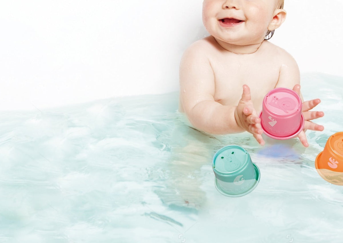 Baby playing with colorful stacking cups in water
