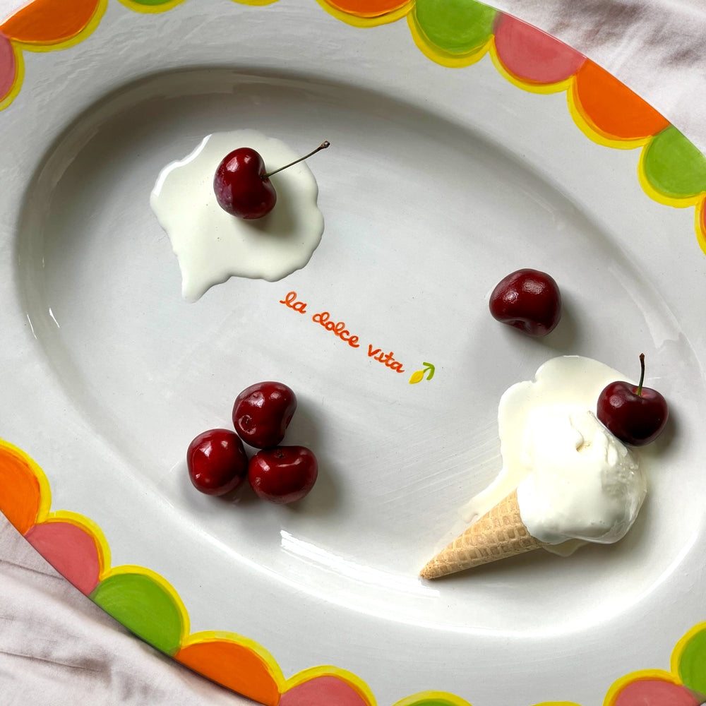 Top view of hand-painted serving tray with la dolce vita script and colorful scalloped rim, with cherries and ice cream