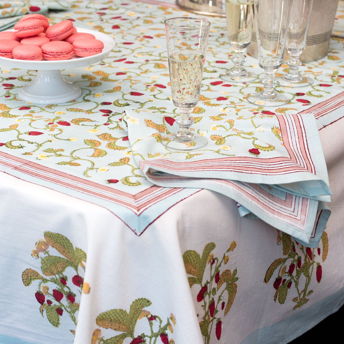 Angled view of Fraises des Bois Napkins, Set of 6 showcasing a red berry and floral pattern with a dining table setting