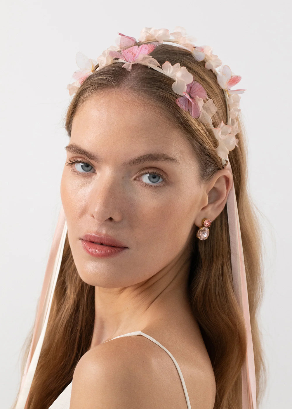 Three-quarter view of Georgina Circlet in Peony showcasing silk organza butterflies, hand-dyed satin flowers and trailing pink ribbons on a white background
