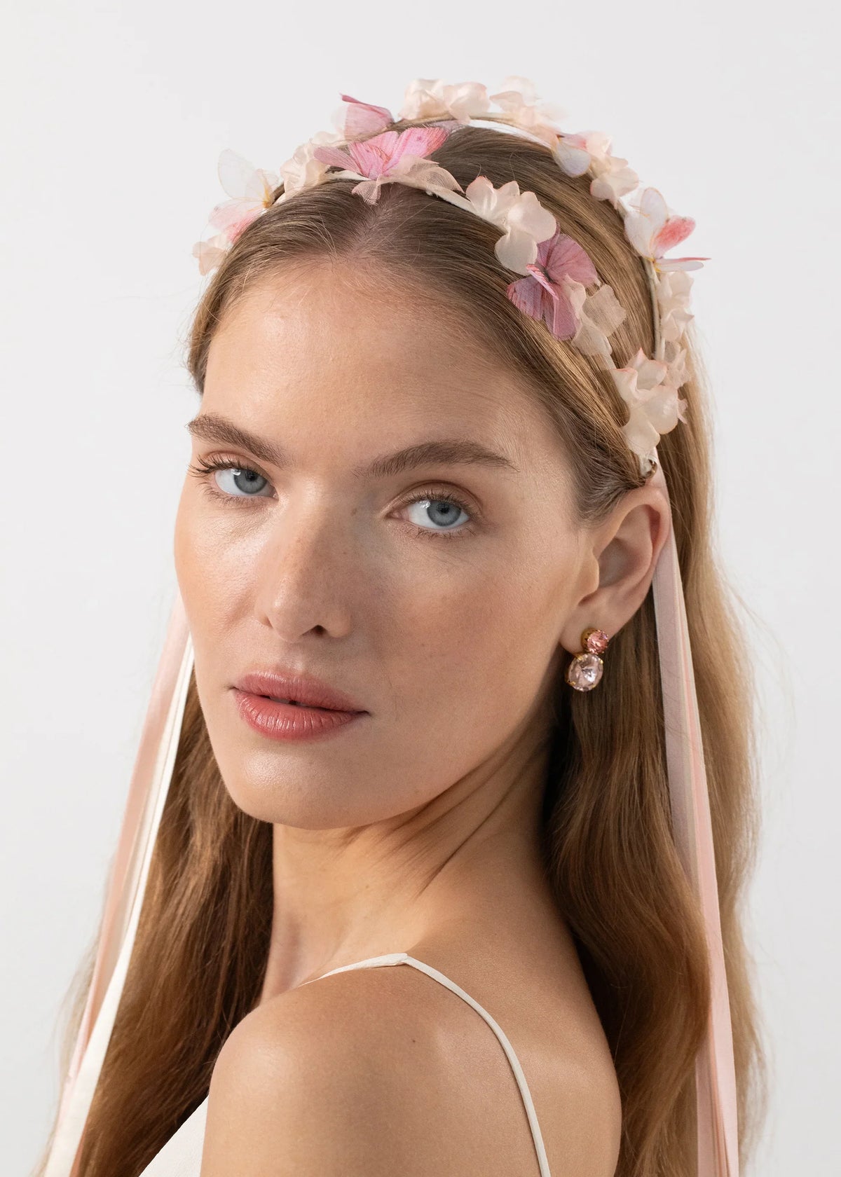 Three-quarter view of Georgina Circlet in Peony showcasing silk organza butterflies, hand-dyed satin flowers and trailing pink ribbons on a white background