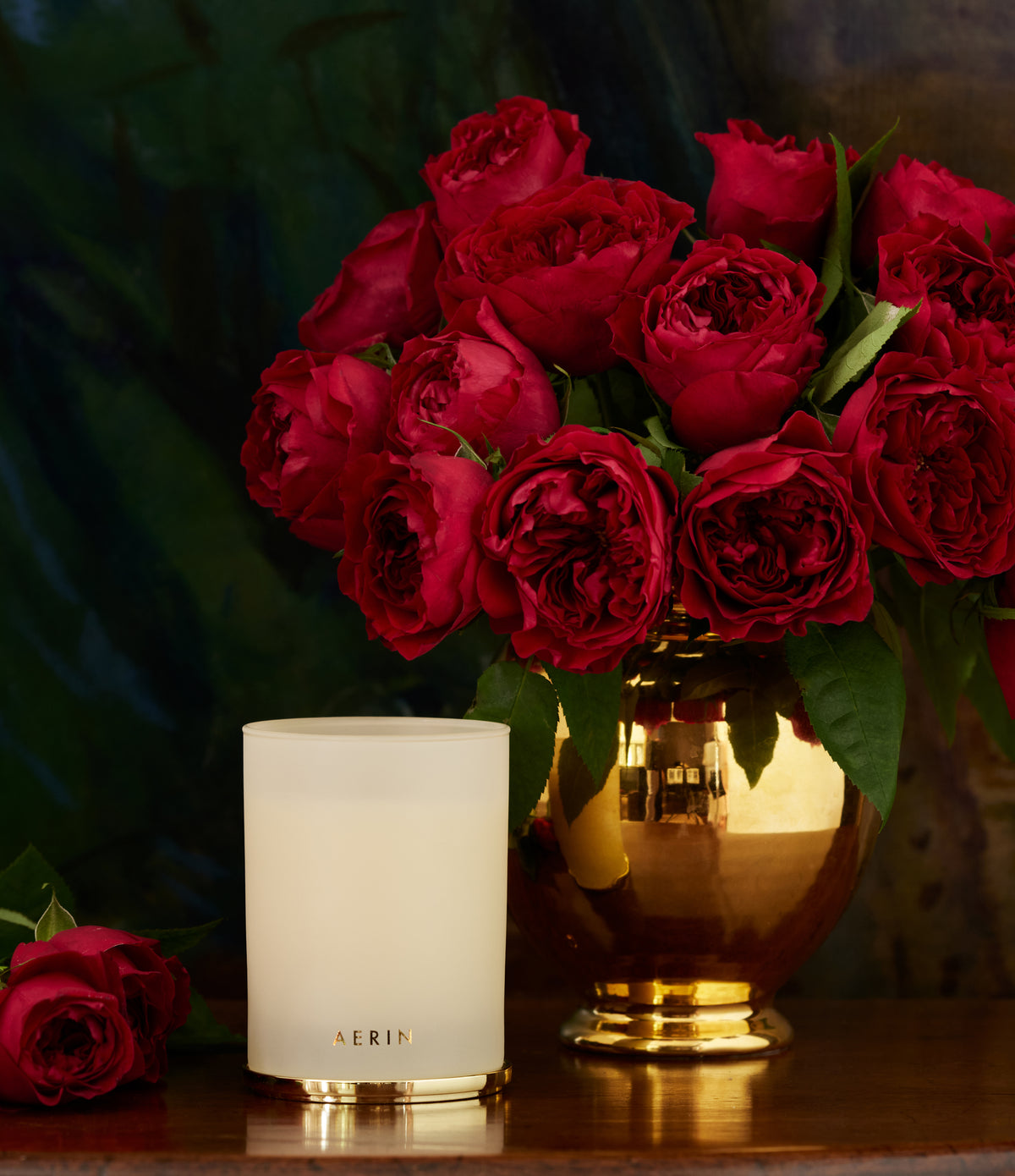 Front view of Holiday Nendaz Cypress Candle in Cream showcasing its glass vessel with red roses on a dark background