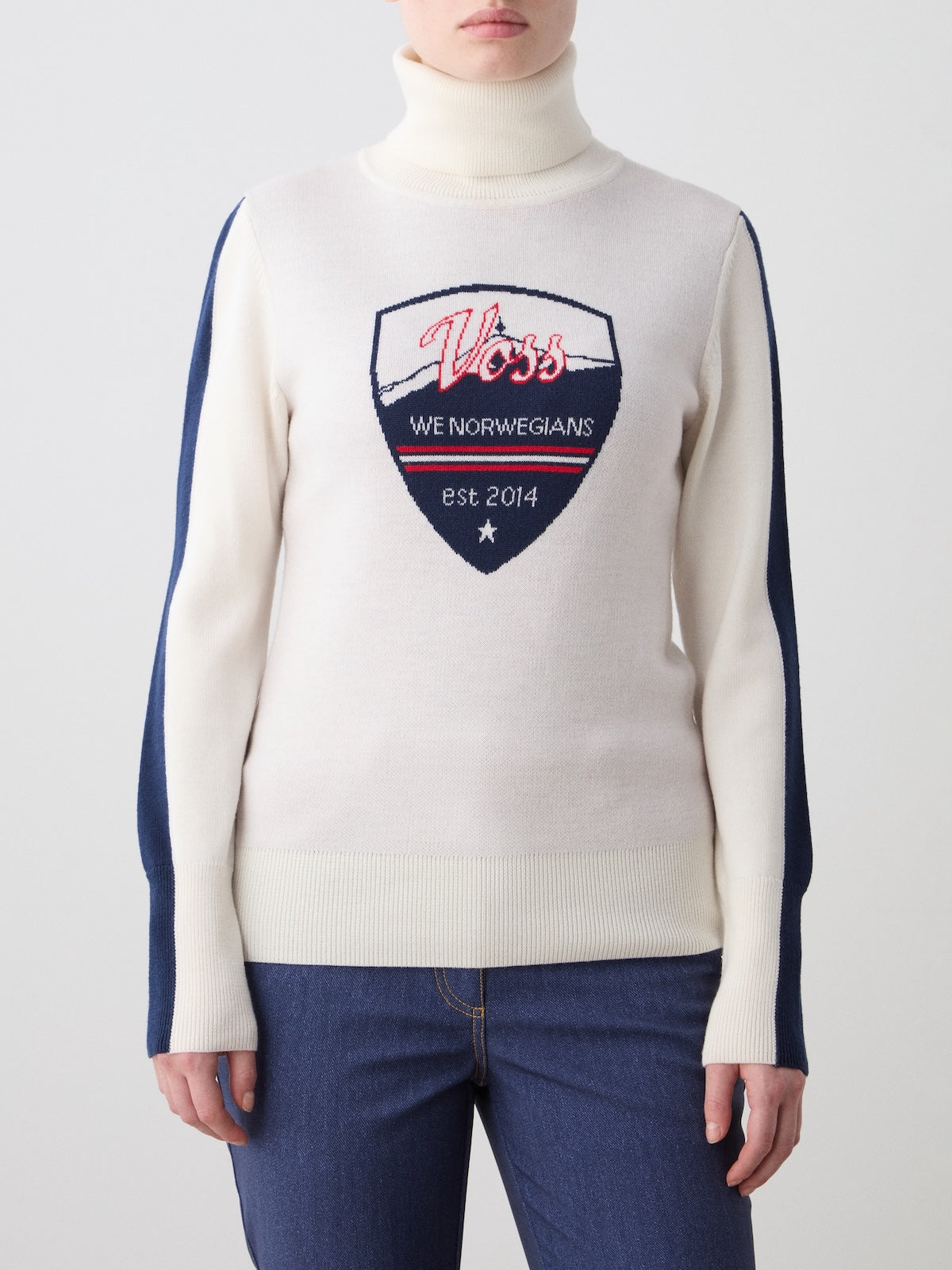 Front view of AfterSki Sweater in Cream showcasing high neck, navy sleeve stripes, and Voss crest with a plain light background