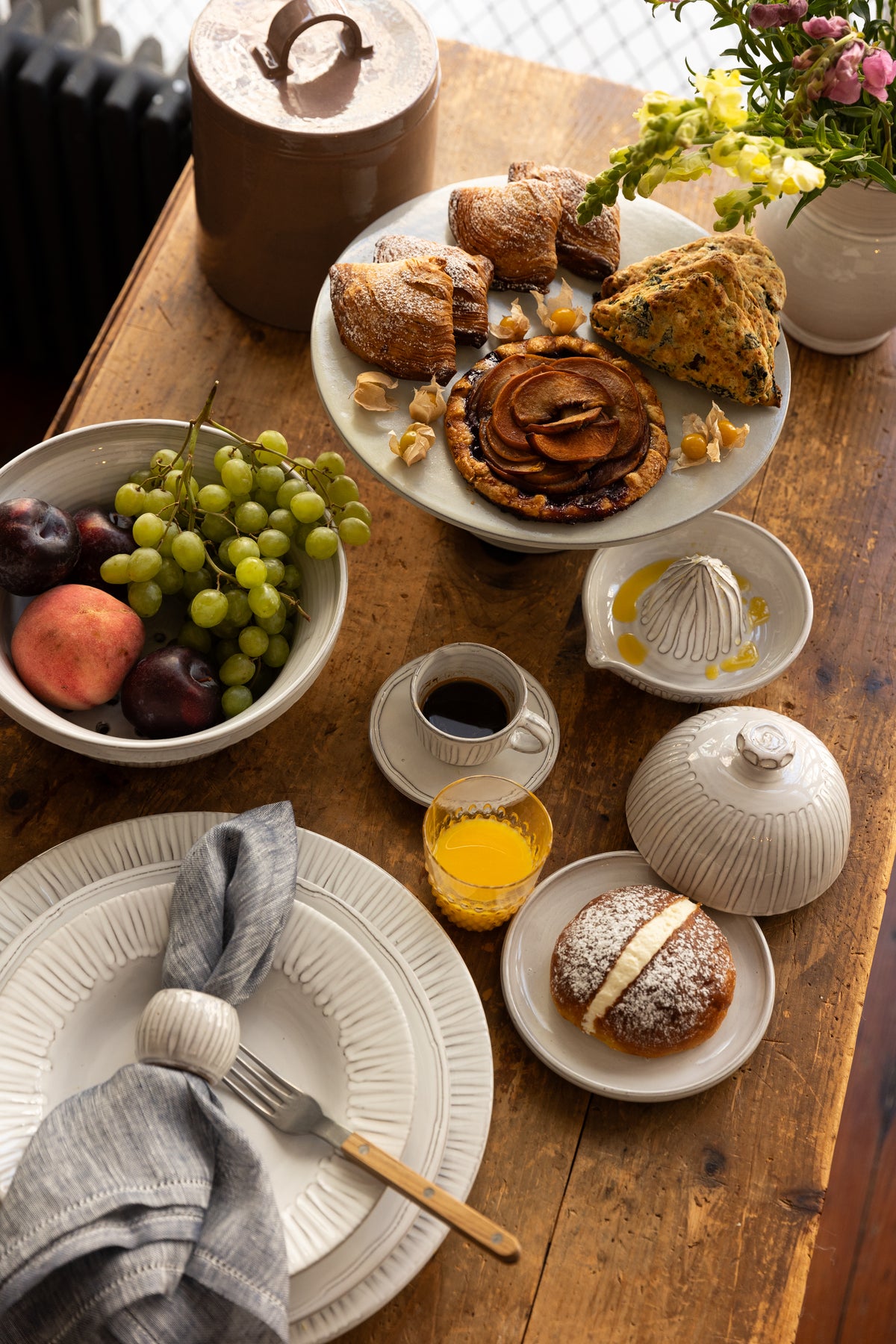 Angled overhead of Radi Fluted Butter Dish showing fluted dome and smooth glaze on a wooden table with pastries