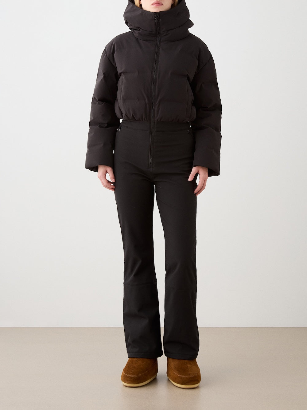 Front view of Aurora Ski Suit in Black showcasing its hood, zipper, and soft-shell lower half on a model