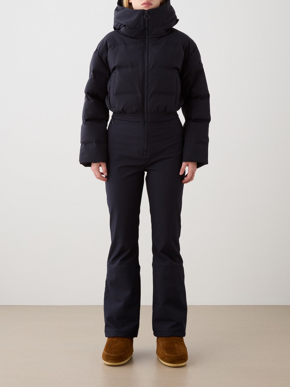 Front view of navy blue Aurora Ski Suit with hood, puffer upper, and soft-shell lower on a model against a light background
