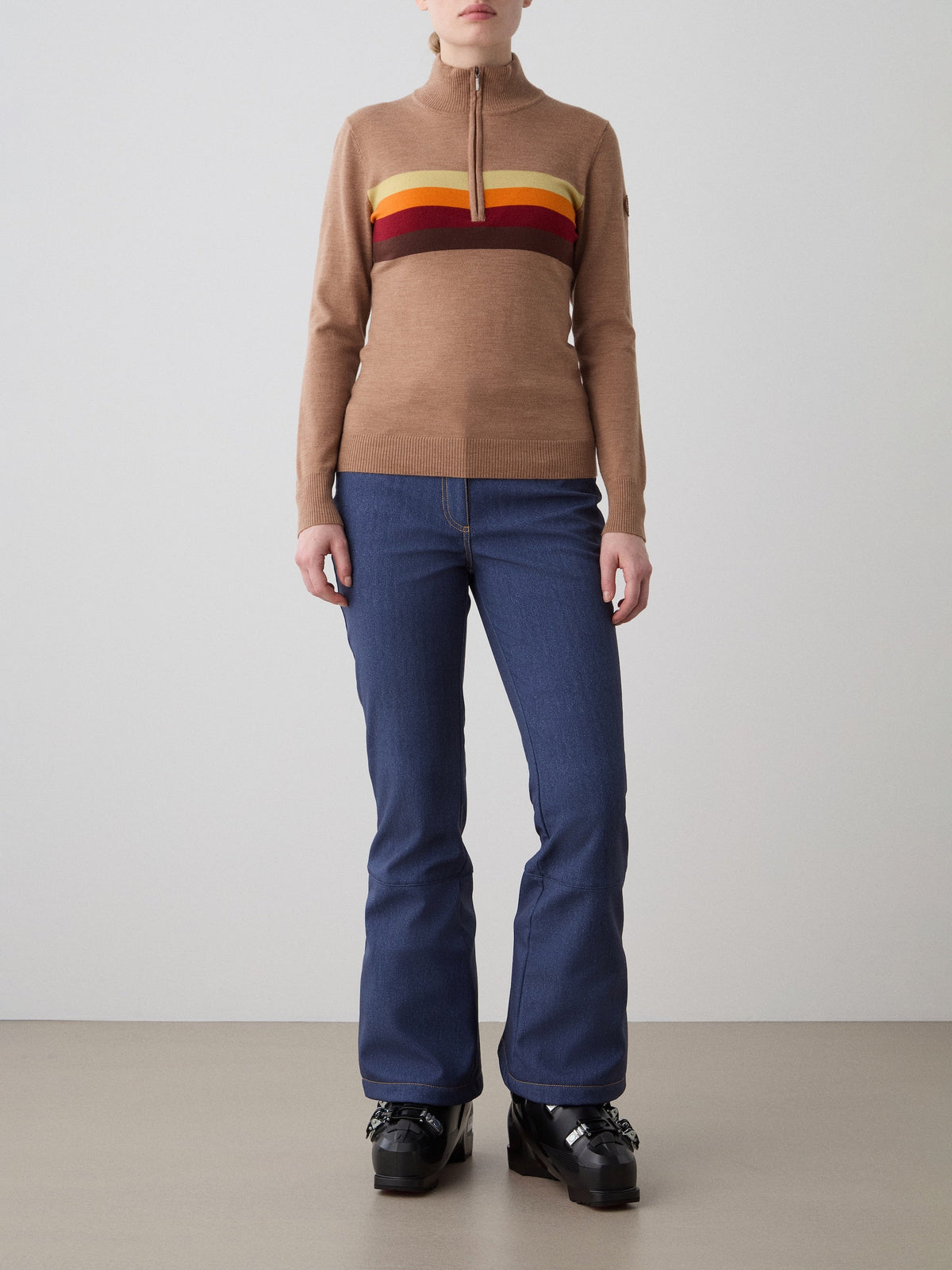 Front view of FreeBird Zip Up in Cinnamon showing its quarter-zip collar and horizontal rainbow stripes on a model