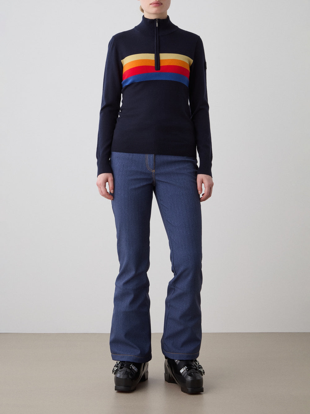Front view of FreeBird zip-up in navy blue showing multicolor chest stripes and half-zip collar on gray background