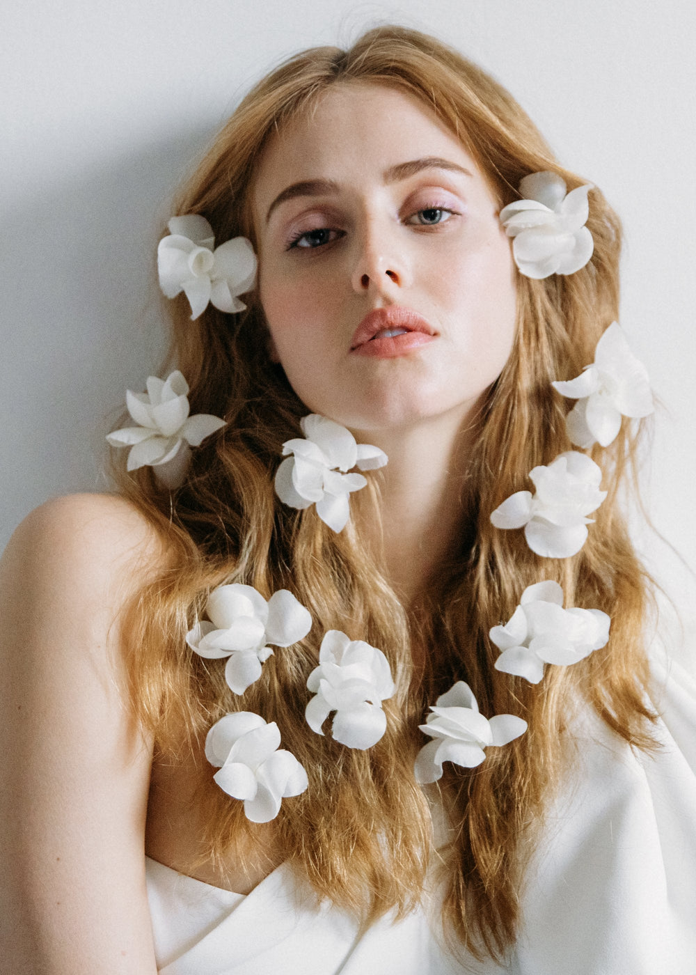 Model wearing large cream Jardinia floral hairpins scattered through long wavy hair against a neutral background