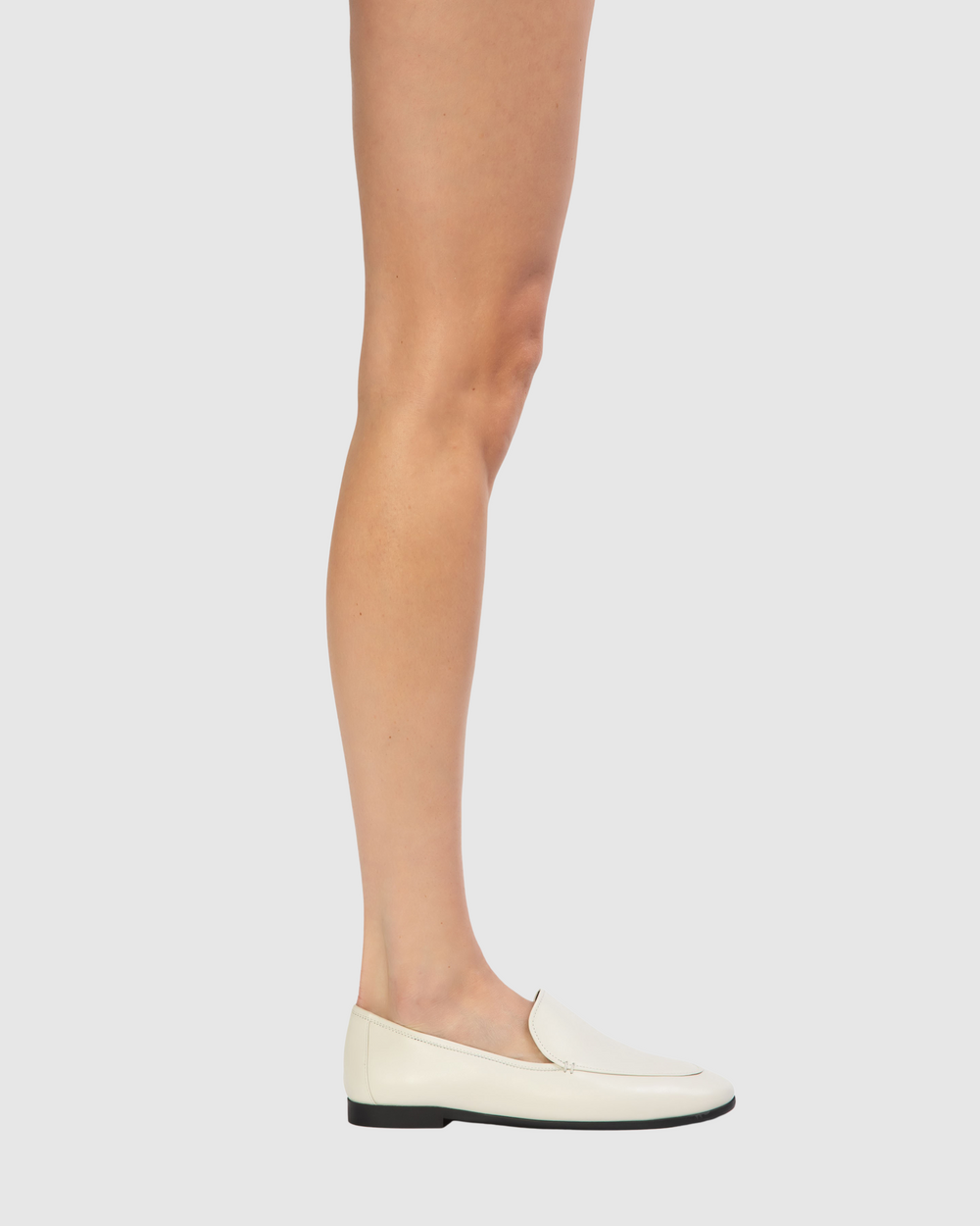 Side view of Allie loafer in coconut leather showcasing round-toe slip-on silhouette and low black sole on light gray background