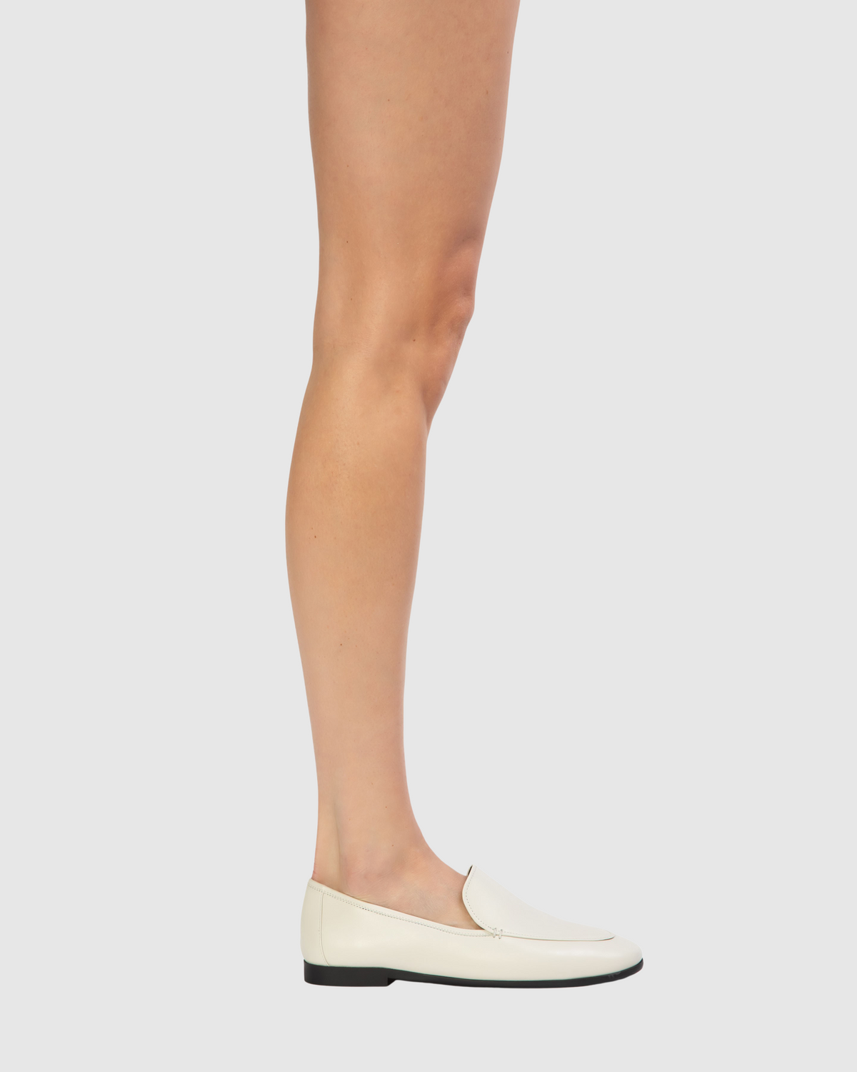 Side view of Allie loafer in coconut leather showcasing round-toe slip-on silhouette and low black sole on light gray background
