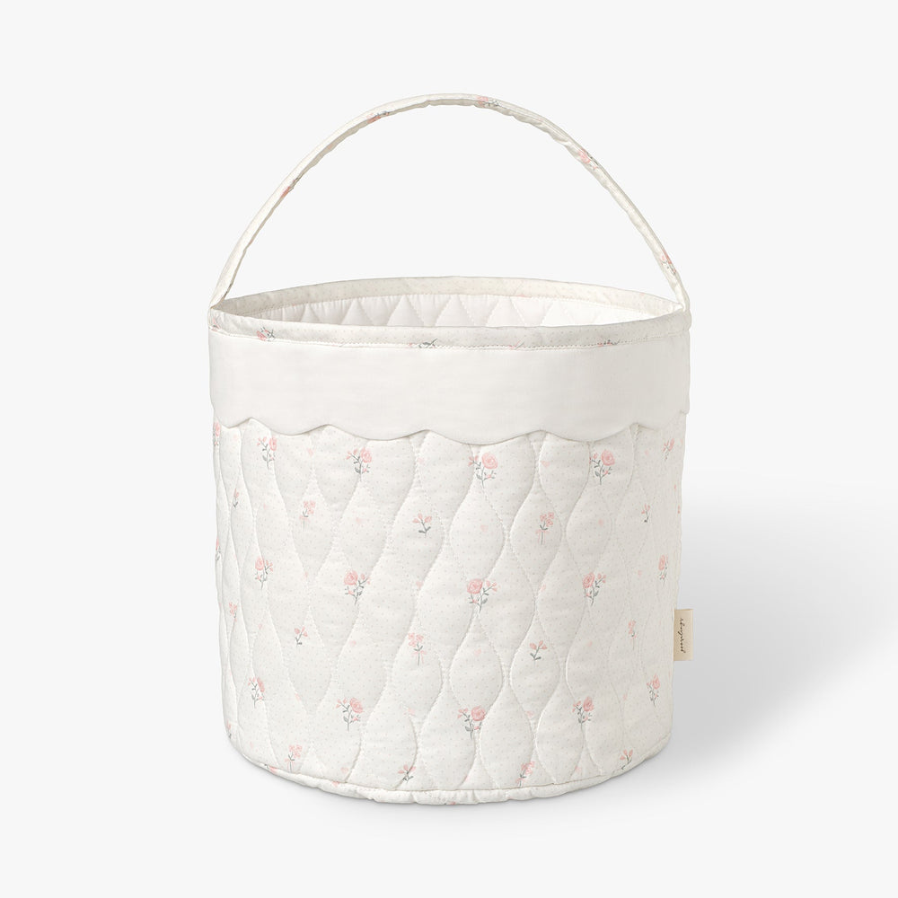 Quilted storage basket with soft pink floral pattern on a white background