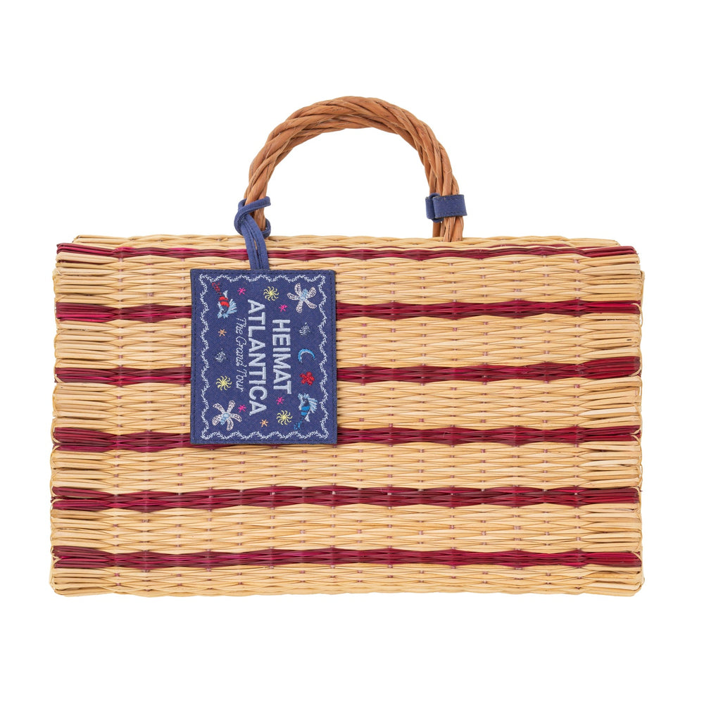 Front view of Grand Tour beach basket with burgundy woven stripes, braided handle, and blue HEIMAT ATLANTICA label