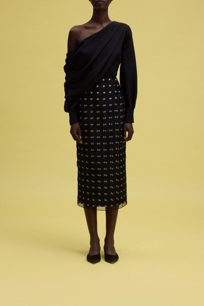Front view of Bethan skirt in navy polka-dot taffeta faille with sheer organza overlay on model against yellow background