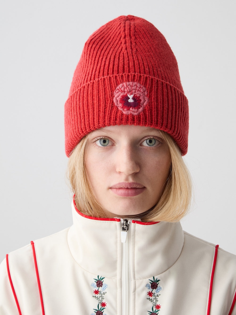 Front view of WN x Markarian Hat in Red showcasing folded cuff and embroidered signature flower on model against light gray background