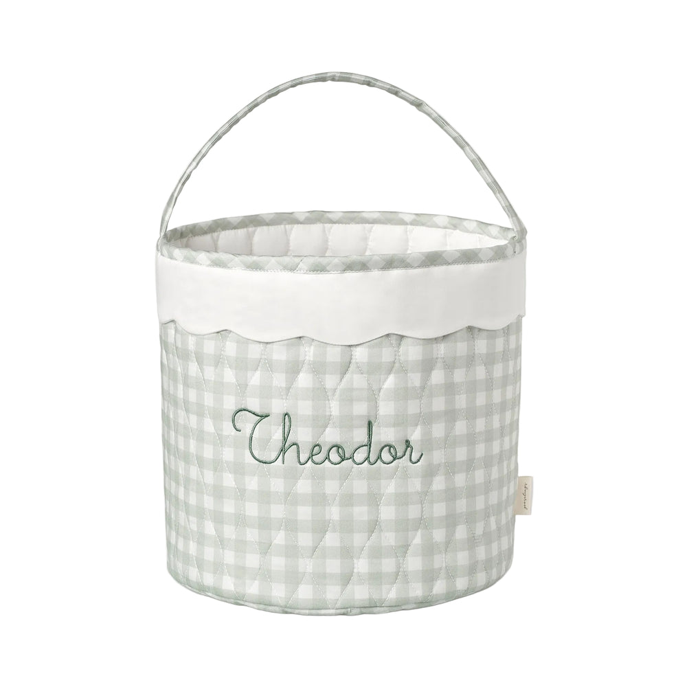 Fabric basket with a green gingham pattern and embroidered name on a white background