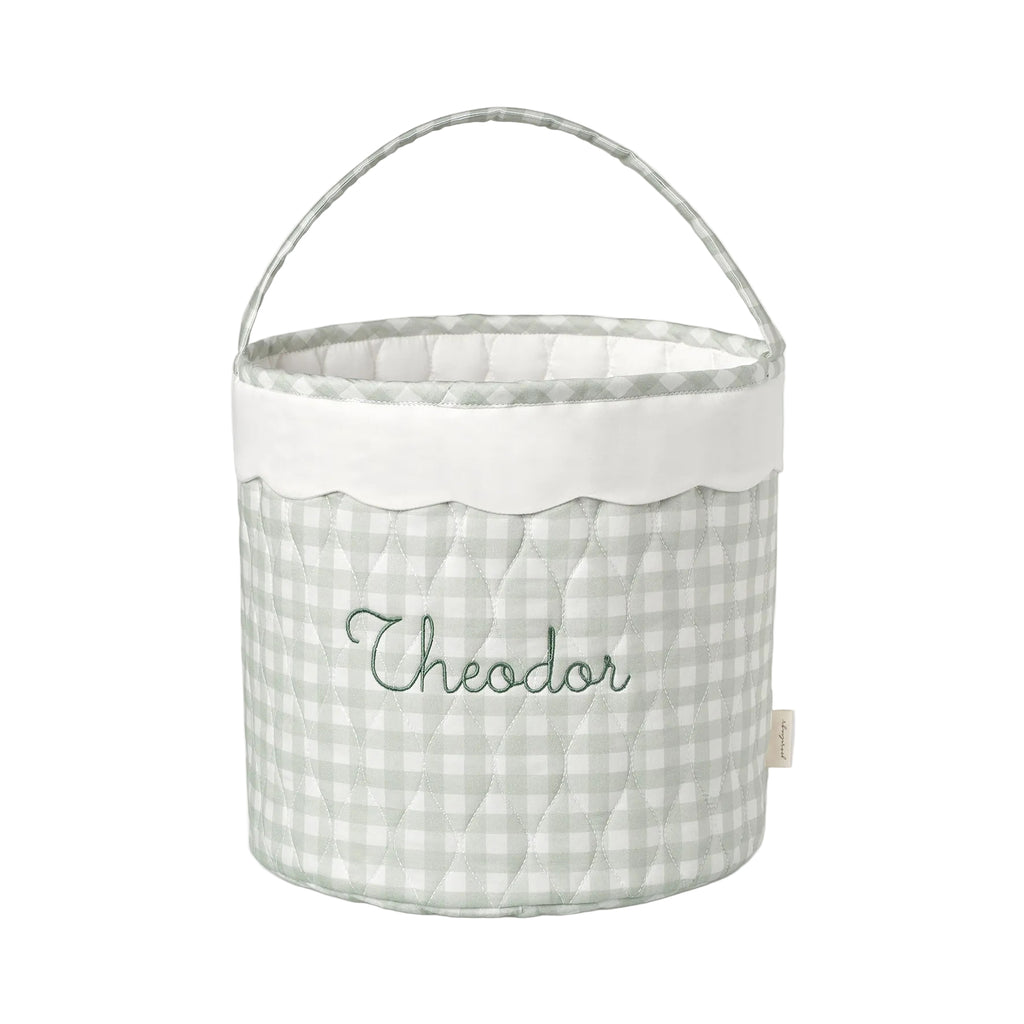 Fabric basket with a green gingham pattern and embroidered name on a white background