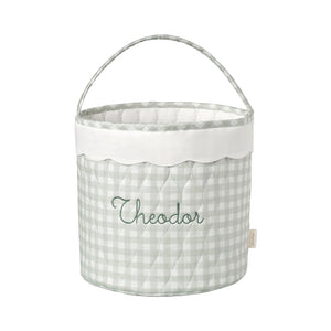 Fabric basket with a green gingham pattern and embroidered name on a white background