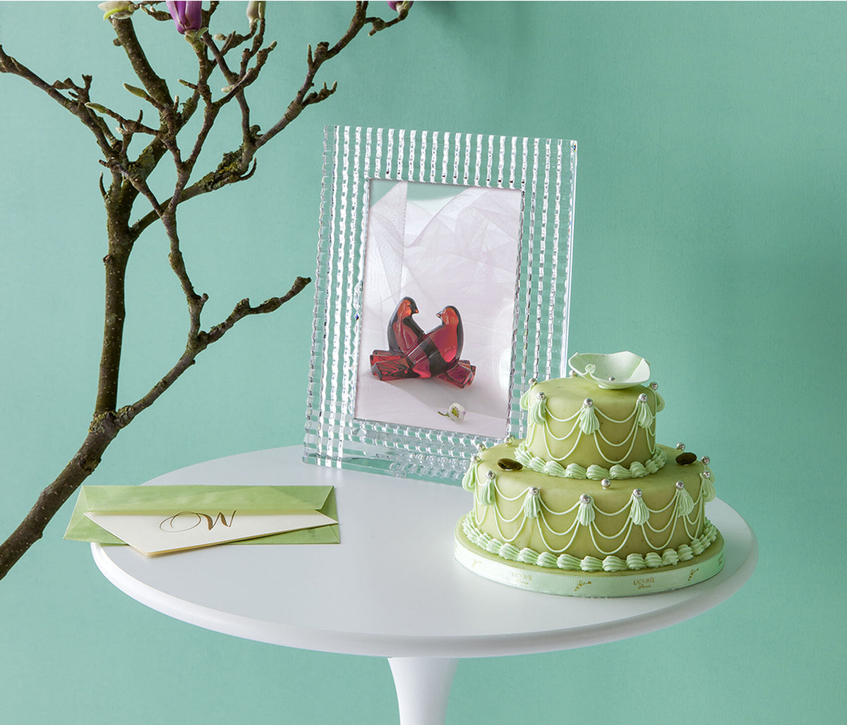 Three-quarter view of Eye Collection crystal picture frame showcasing vertical ribbed cuts and 5x7 opening on a white pedestal with mint-green background