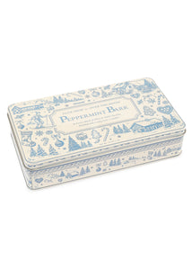 Angled view of Tuck Shop for Over The Moon Peppermint Bark showcasing a blue and white keepsake tin on a white background
