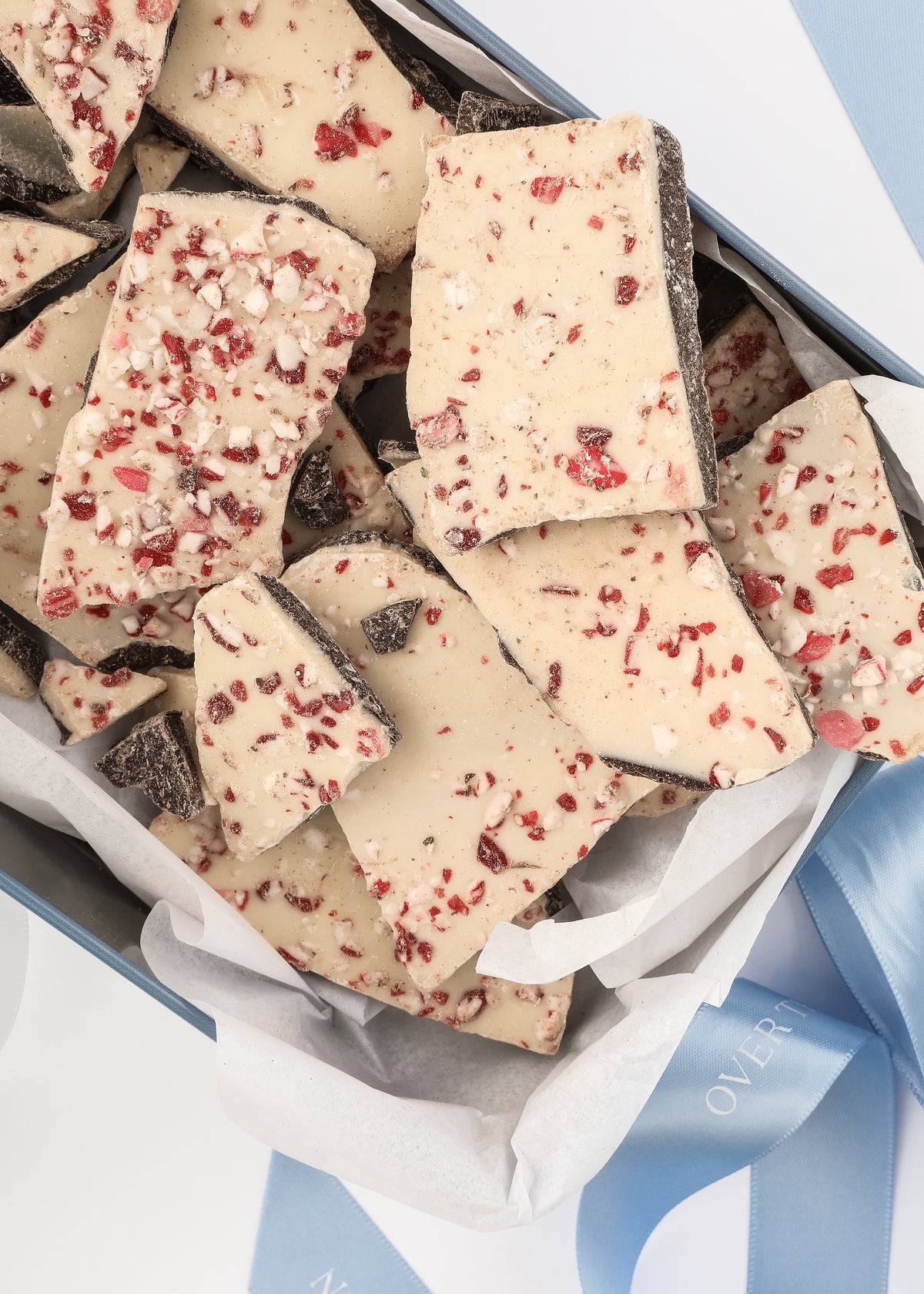 Top view of Tuck Shop for Over The Moon Peppermint Bark showcasing peppermint topping in a keepsake tin