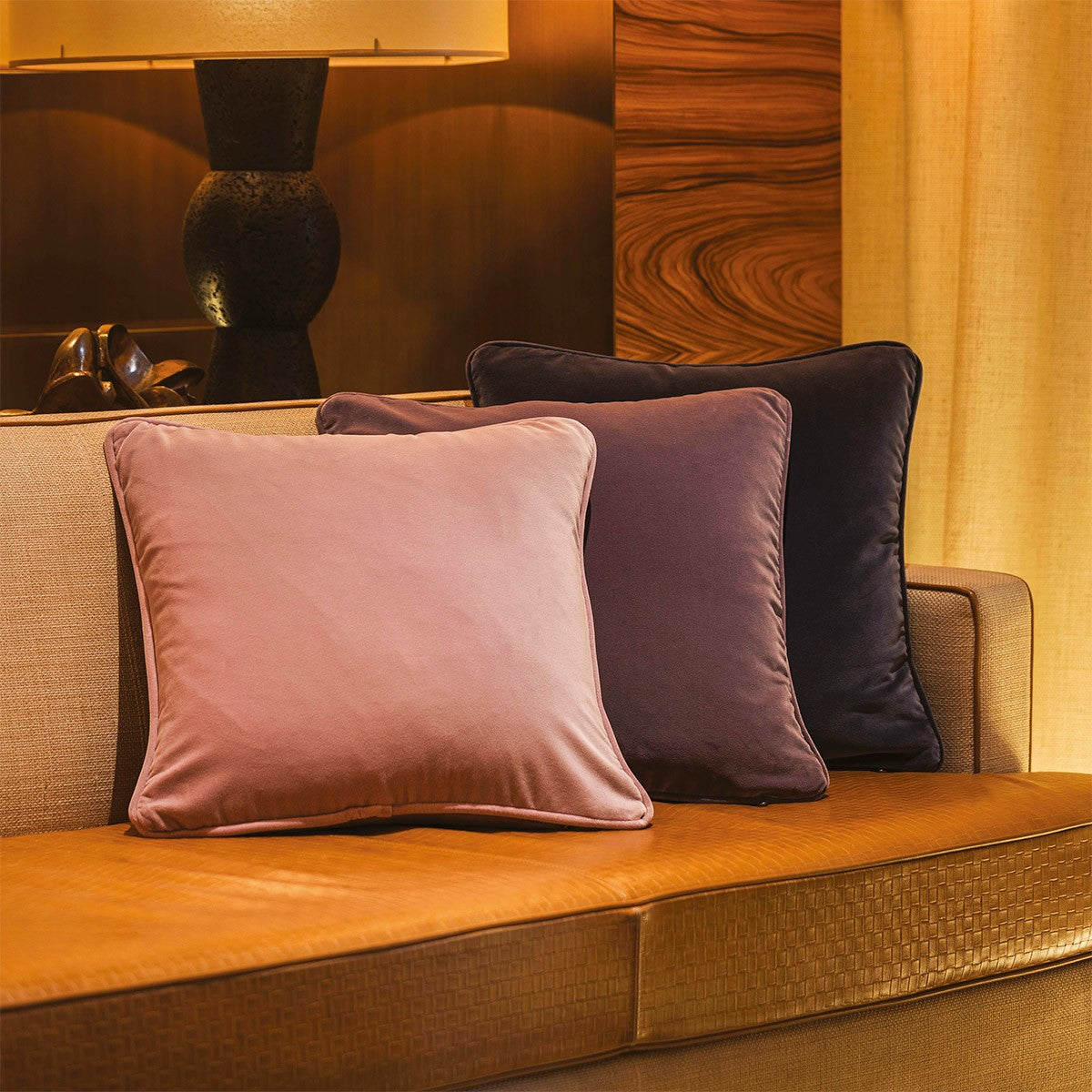 Front view of Divan Pillow showing three cotton velour cushions in pink, mauve and dark blue with piped edges on a sofa
