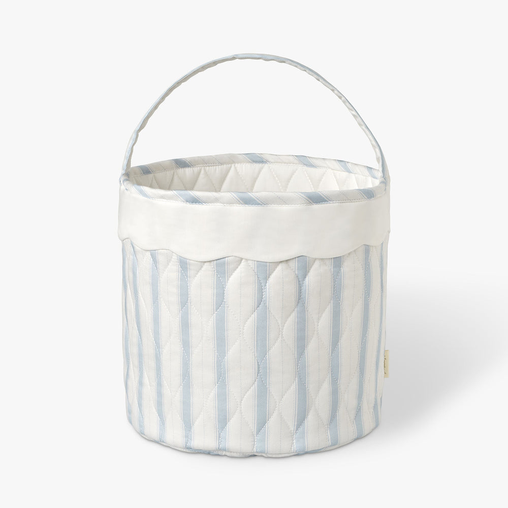 Blue ad white striped quilted basket with handle on while background.