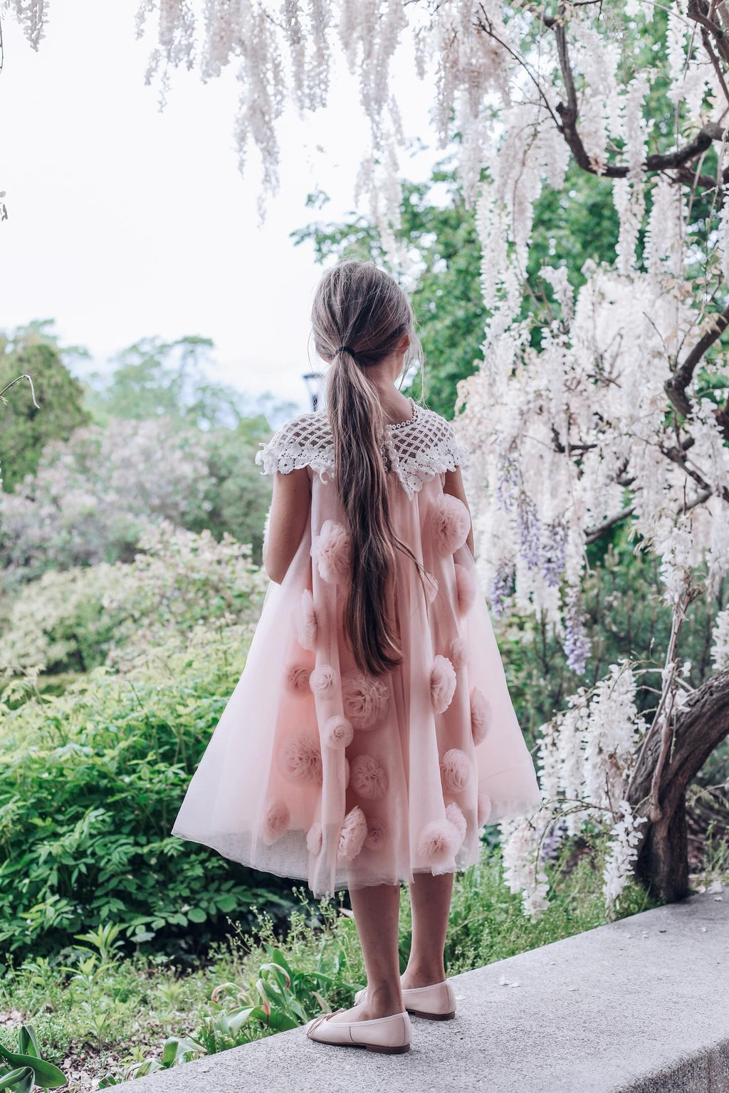 Back view of  girls pink tulle dress with flower details 