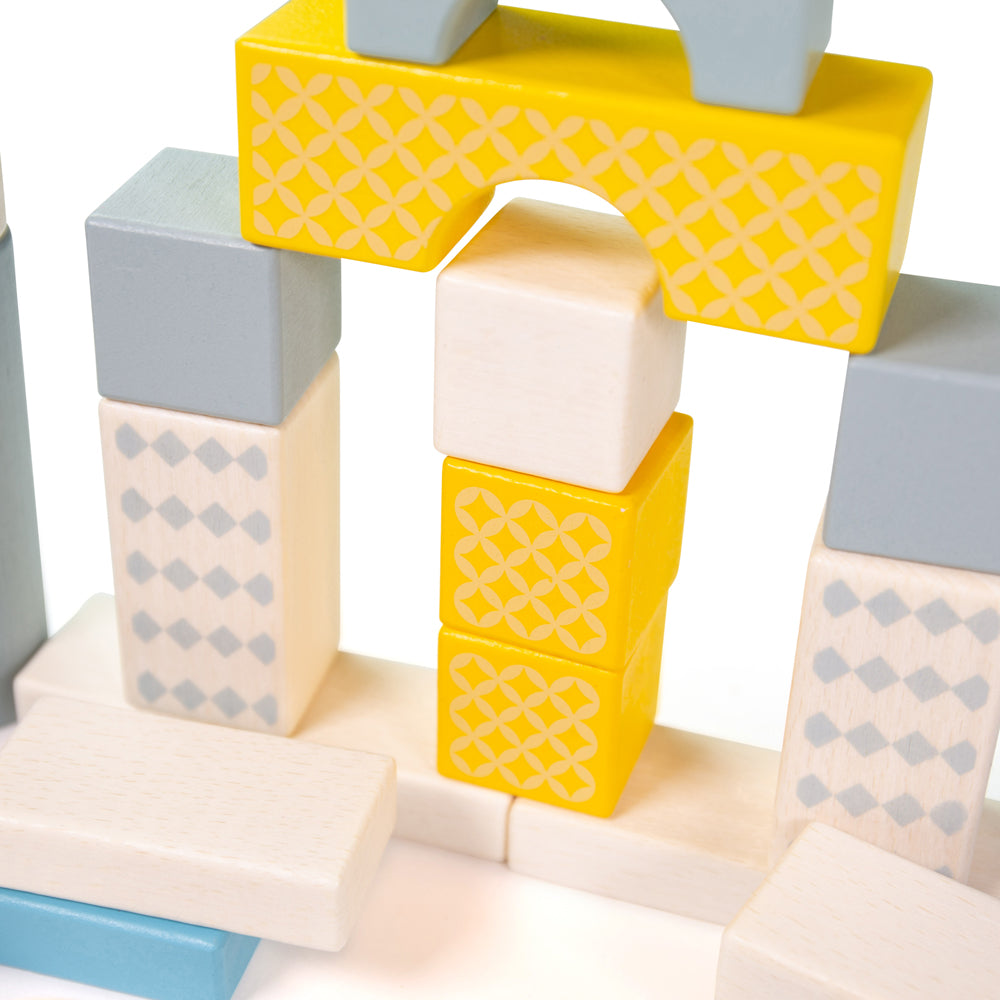 Close-up of Drum of 50 Bricks showcasing colorful patterned wooden shapes arranged into a structure on a white background